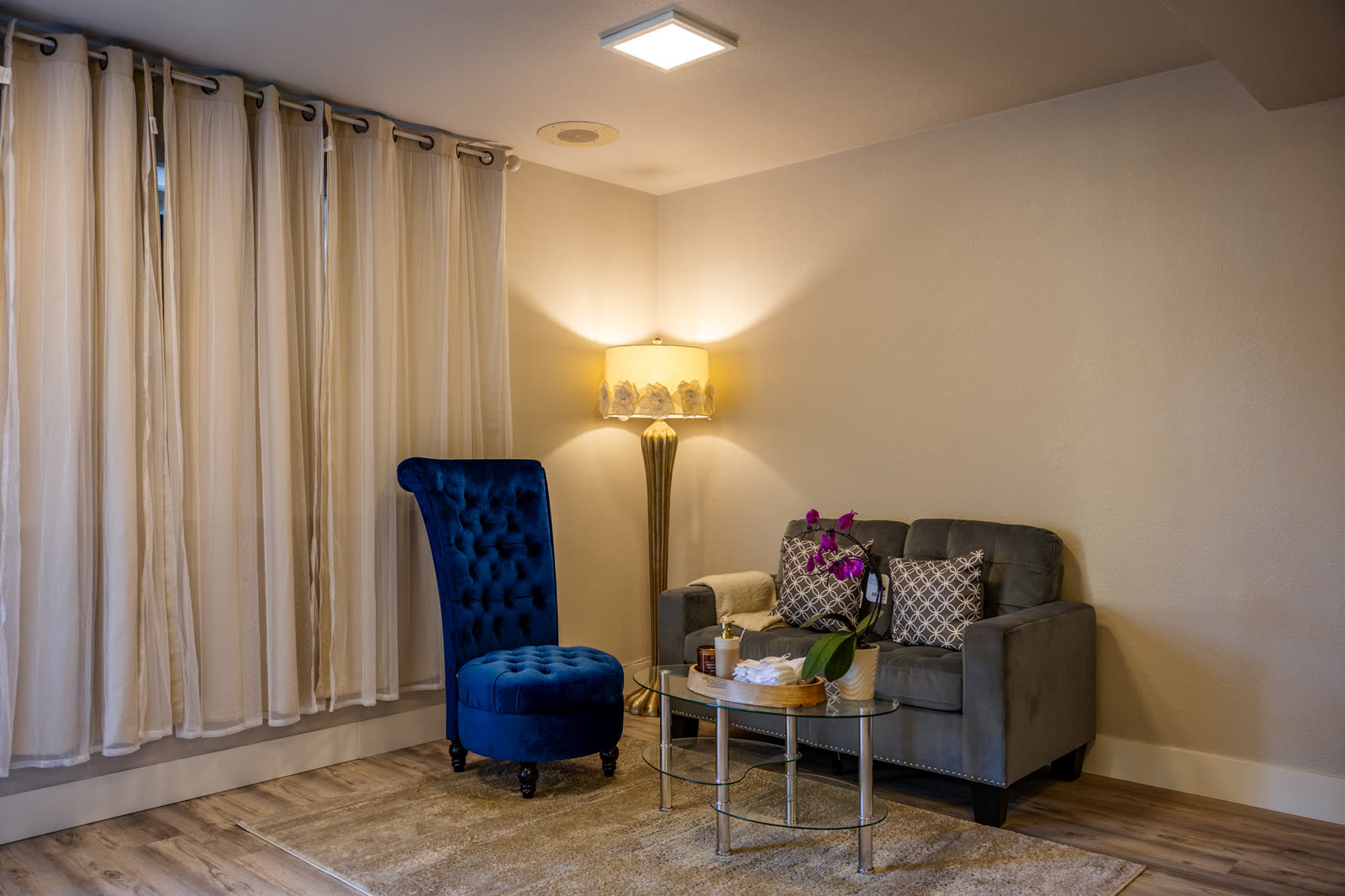 Hannah Beauty & Spa Placerville &mdash; warm intimate lounge with blue velvet chair and grey sofa